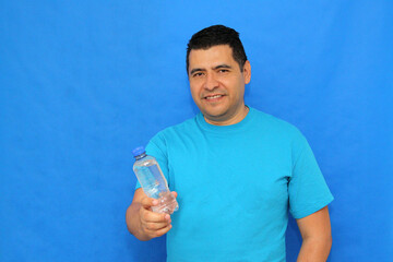 A 40-year-old dark-skinned Latino man shows a plastic bottle of water to stay hydrated and maintain...