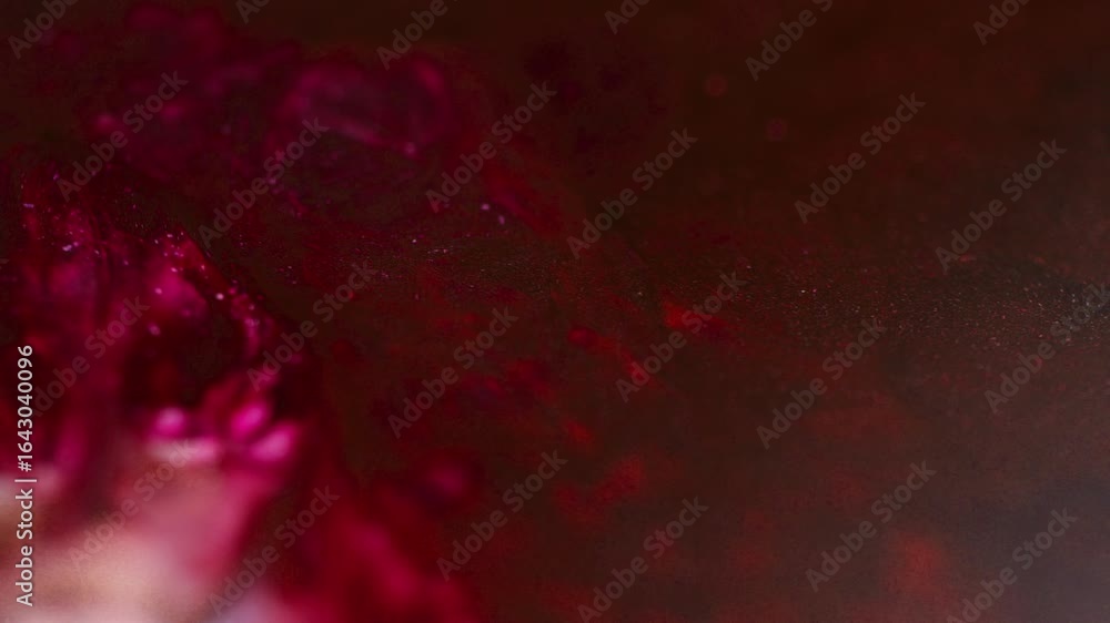 Poster macro shot of red, pink, and burgundy inks moving and bubbling across the surface, creating abstract
