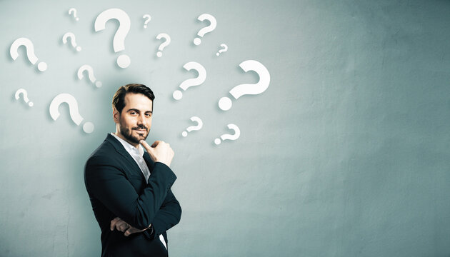 Thoughtful businessman standing in front of a wall filled with floating question marks, symbolizing decision-making and problem solving. - Powered by Adobe
