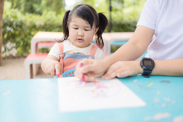 A mother and her little daughter are sitting together coloring,Portrait of a cheerful little...