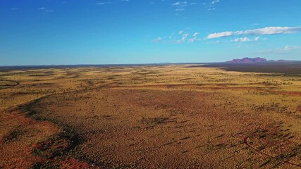 Aerial view of the vast, arid Australian outback, showcasing contrasting red earth meeting the clear blue sky, Ayers Rock, Northern Territory, Australia. - Powered by Adobe