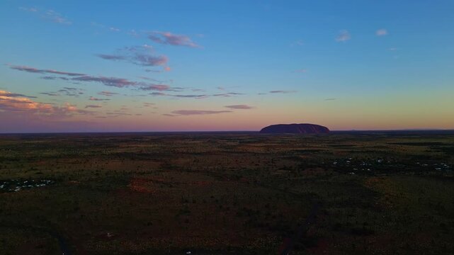 Aerial view of Uluru-Kata Tjuta National Park, a vast desert landscape with the iconic Uluru monolith bathed in the warm hues of the setting sun, Ayers Rock, Northern Territory, Australia.