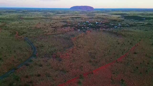 Aerial view of Ayers Rock with its unique landscape and distant rock formations, creating a captivating contrast between the red earth and the horizon, Ayers Rock, Northern Territory, Australia.