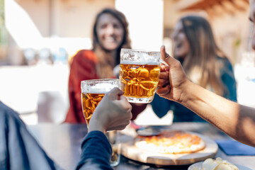 Friends toasting with beer mugs at outdoor restaurant