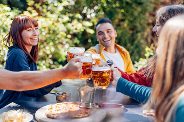Friends toasting with beer mugs at outdoor party