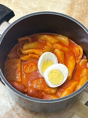 Spicy Korean tteokbokki with chewy rice cakes in a vibrant red sauce, topped with sesame seeds and...