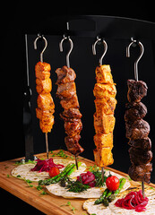 Delicious skewers served on a wooden platter with fresh vegetables and herbs