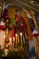 Vertical photo of a church icon and candles out of focus in the foreground