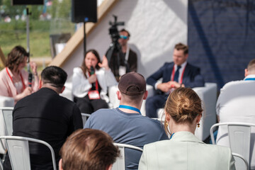 Group of professionals engaging in seminar event. Attendees focus on speaker discussions indoors.