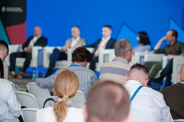 Professional panel discussion with attendees in focus. Engaged audience participates in business seminar.