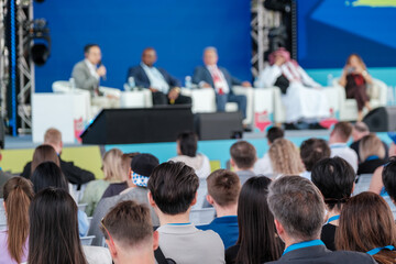 Conference audience engages in a panel discussion with professionals and guest speakers on stage.