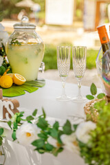 lemonade jar with lemons and herbs and two champagne glasses 