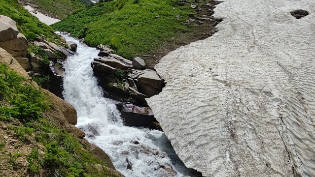 A raging, cold, energetic mountain river with a large snowfields, located in the Kaskasu gorge, Turkestan region, Republic of Kazakhstan.