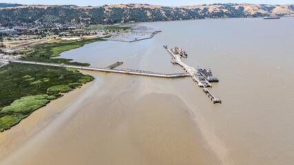 aerial landscape view of area around Carquinez Strait, with large pier and marina along coastline and partly wooded, dried and hilly landscape of Briones Regional Park in background, Martinez, CA,USA