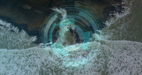 Displaying waves rolling along rocky shoreline in aerial view, with concentric circular HUD overlay