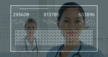 Smiling doctor in blue scrubs reviewing codes on overlay in hospital with stethoscope, copy space