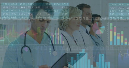 Reviewing medical team analyzing digital charts in hospital corridor, with tablet and stethoscopes