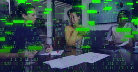 Three women in professional attire analyzing charts in office meeting room, with smartphone, laptop