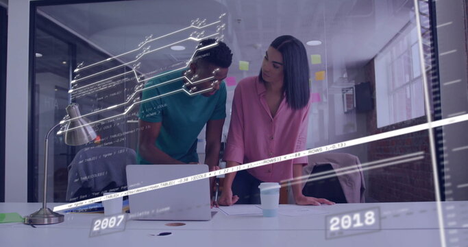 Leaning two coworkers collaborating in meeting room, with laptop sticky notes timeline graphics