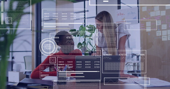 Collaborating colleagues wearing red sweater and white tee reviewing laptop, sticky notes at office - Powered by Adobe