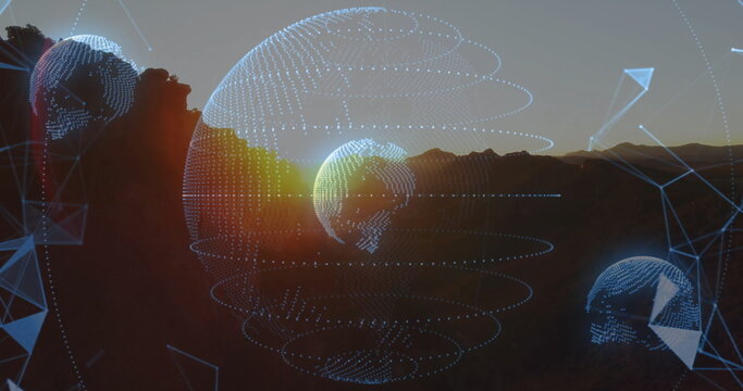 Fototapeta Floating three wireframe globes glowing with blue dots above mountain ridge at sunset, with nodes