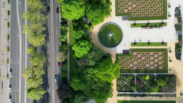 Aerial view of a road running parallel to a lush green park with cars moving along the asphalt, creating a contrast, Brussels, Belgium.