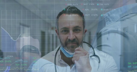 Pulling surgical mask beneath stethoscope, male physician in hospital hall with data overlays