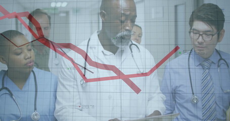 Holding tablet and stethoscope, doctor in white coat reviewing red trend grid in hospital corridor