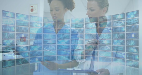 Nurse and doctor analyzing curved digital screens in corridor, with tablet clipboard stethoscope