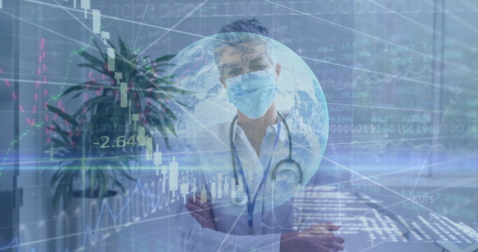 Analyzing financial data overlays, senior doctor standing in exam room, with stethoscope and mask - Powered by Adobe