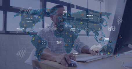 Analyzing digital map overlay, IT analyst interacting with monitor and mouse at desk in office