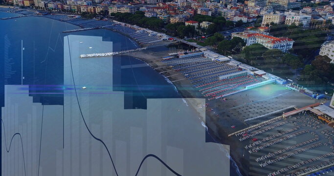 Displaying beach umbrellas and lounge chairs lining shore at coastal town, with piers and buildings - Powered by Adobe