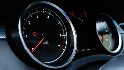 A car dashboard with a red light on the left side