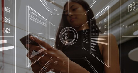Holding smartphone, woman in black sleeveless top using holographic interface in lobby, data charts