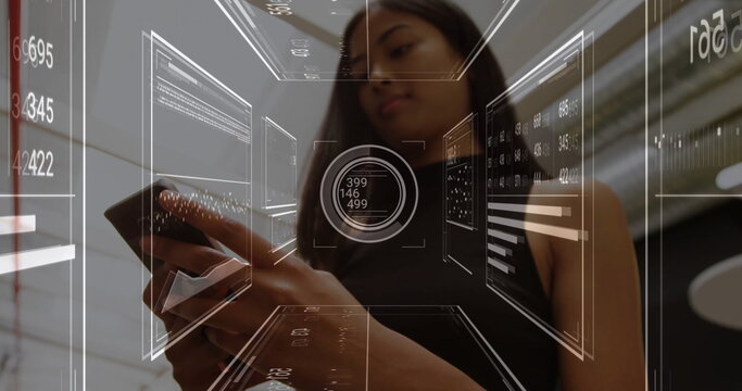 Holding smartphone, woman in black sleeveless top using holographic interface in lobby, data charts