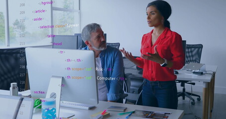 Gesturing woman wearing red blouse discussing software in open-plan office, with HTML code overlay