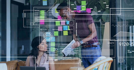 Collaborating colleagues reviewing data overlays on laptop tablet in office lounge with post-its