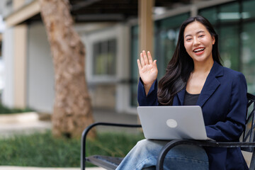 Asian businesswoman waving during video conference outdoors