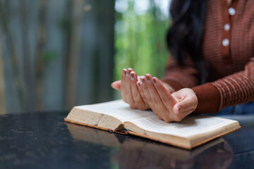 Woman praying with open holy book on table