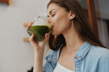Young woman enjoying healthy green smoothie in modern kitchen, promoting wellness and healthy...