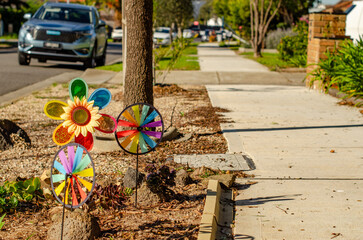 Colorful garden pinwheels and a playful sunflower decoration placed in a nature strip beside a...