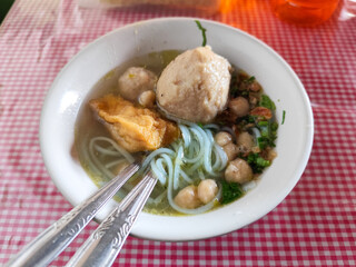 Meatball. A bowl of meatballs complete with yellow noodles, crispy fried dumplings, etc., served...