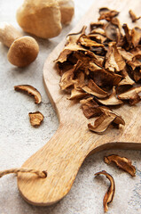 Dried mushrooms on wooden cutting board with fresh mushrooms