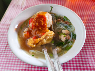 Meatball. A bowl of meatballs complete with yellow noodles, crispy fried dumplings, etc., served...