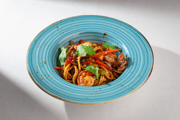 Traditional Korean stir-fried seaweed served with sliced pork, onion, spicy sauce and fresh herbs on a rustic ceramic plate, top-down view