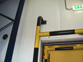 Yellow and black safety bars near an exit door and emergency exit sign.