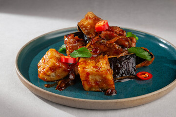 Pan-fried tofu cubes with grilled eggplant, chicken, chili pepper and fresh herbs in spicy Korean...