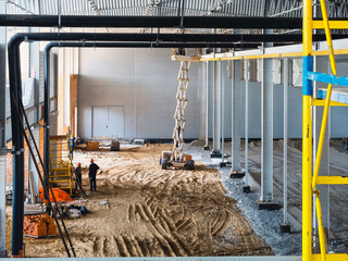 Inside a large industrial building under construction with workers on site.