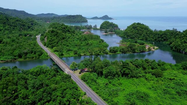 Long Road Bridge Surrounded by Tropical Forest, River, and Mountains in Aceh, Indonesia