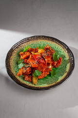 Spicy Korean chicken dish with red pepper, zucchini, onion, sesame seeds and cilantro served on a...